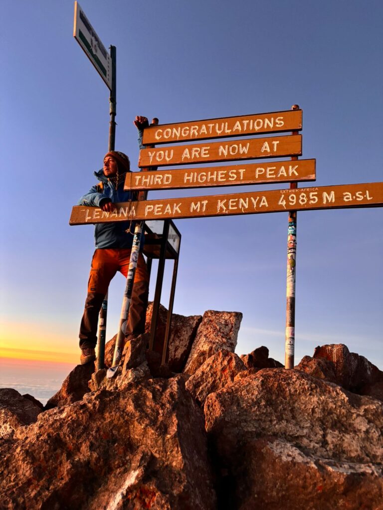 Two trekkers celebrating at the Point Lenana summit sign, Mount Kenya